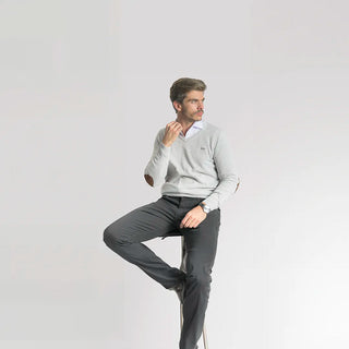 Hombre sentado con suéter gris y pantalón negro. 