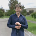 Hombre sonriendo en exterior con camisa azul oscuro