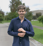 Hombre sonriendo en exterior con camisa azul oscuro