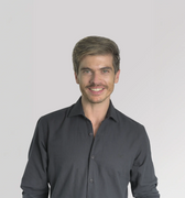 Hombre sonriendo con camisa negra sobre fondo blanco.