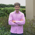 Hombre con camisa de cuadros fucsia en un jardín. 