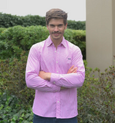 Hombre con camisa de cuadros fucsia en un jardín. 